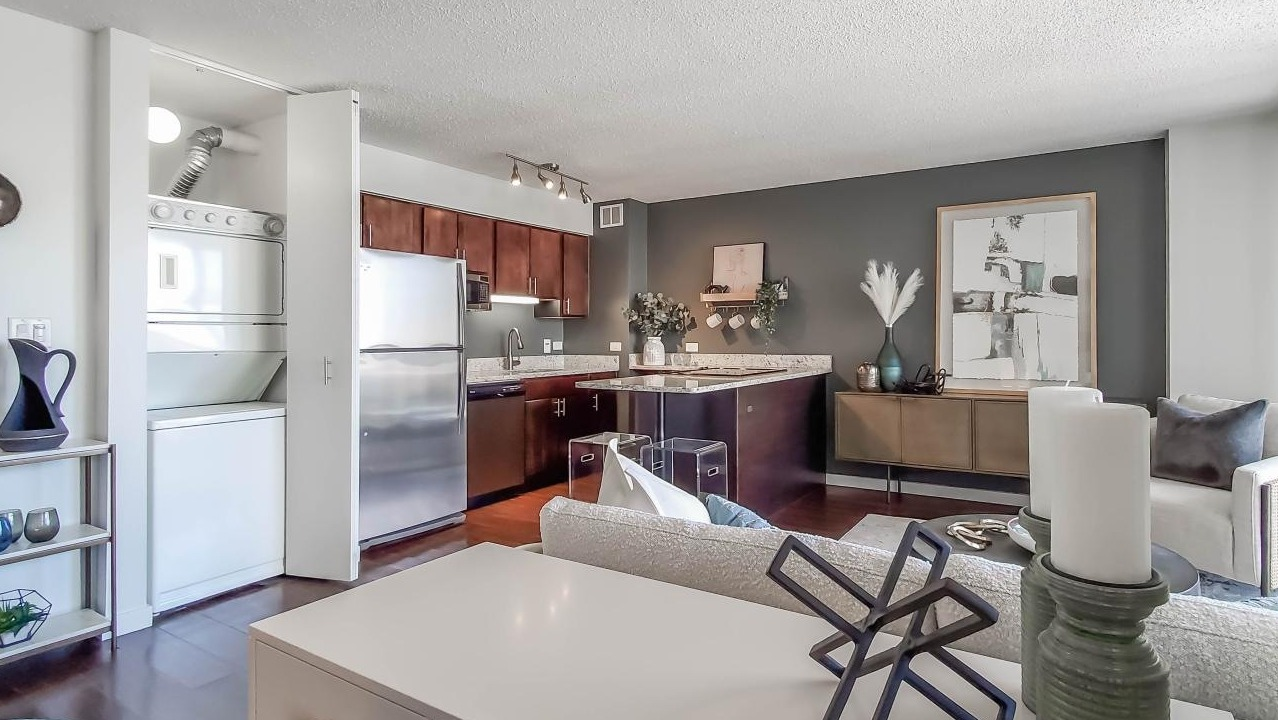 Open kitchen and living area at One Superior Place Apartments with granite counters, stainless appliances, and modern furnishings
