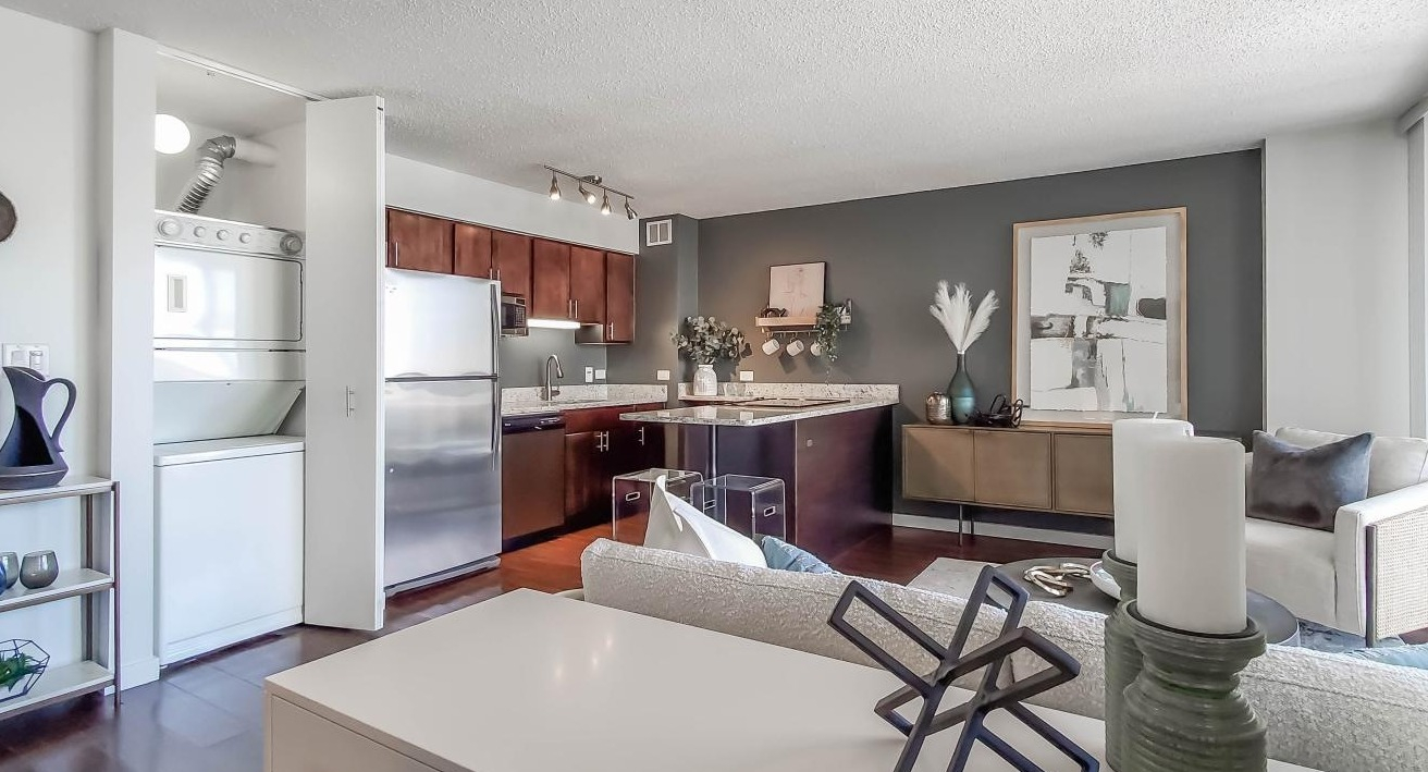 Open kitchen and living area at One Superior Place Apartments with granite counters, stainless appliances, and modern furnishings