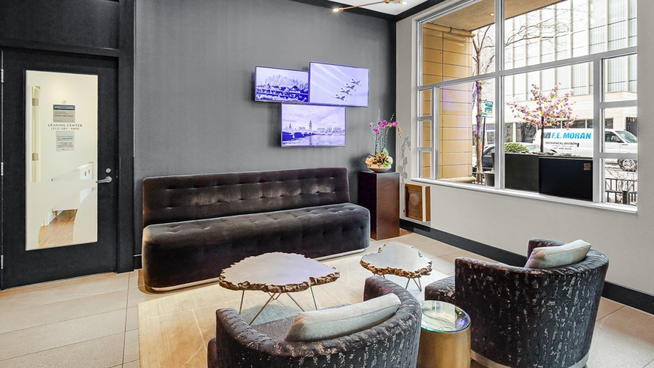 Stylish lobby at One Superior Place Apartments with dark seating, modern lighting, and large windows welcoming natural light