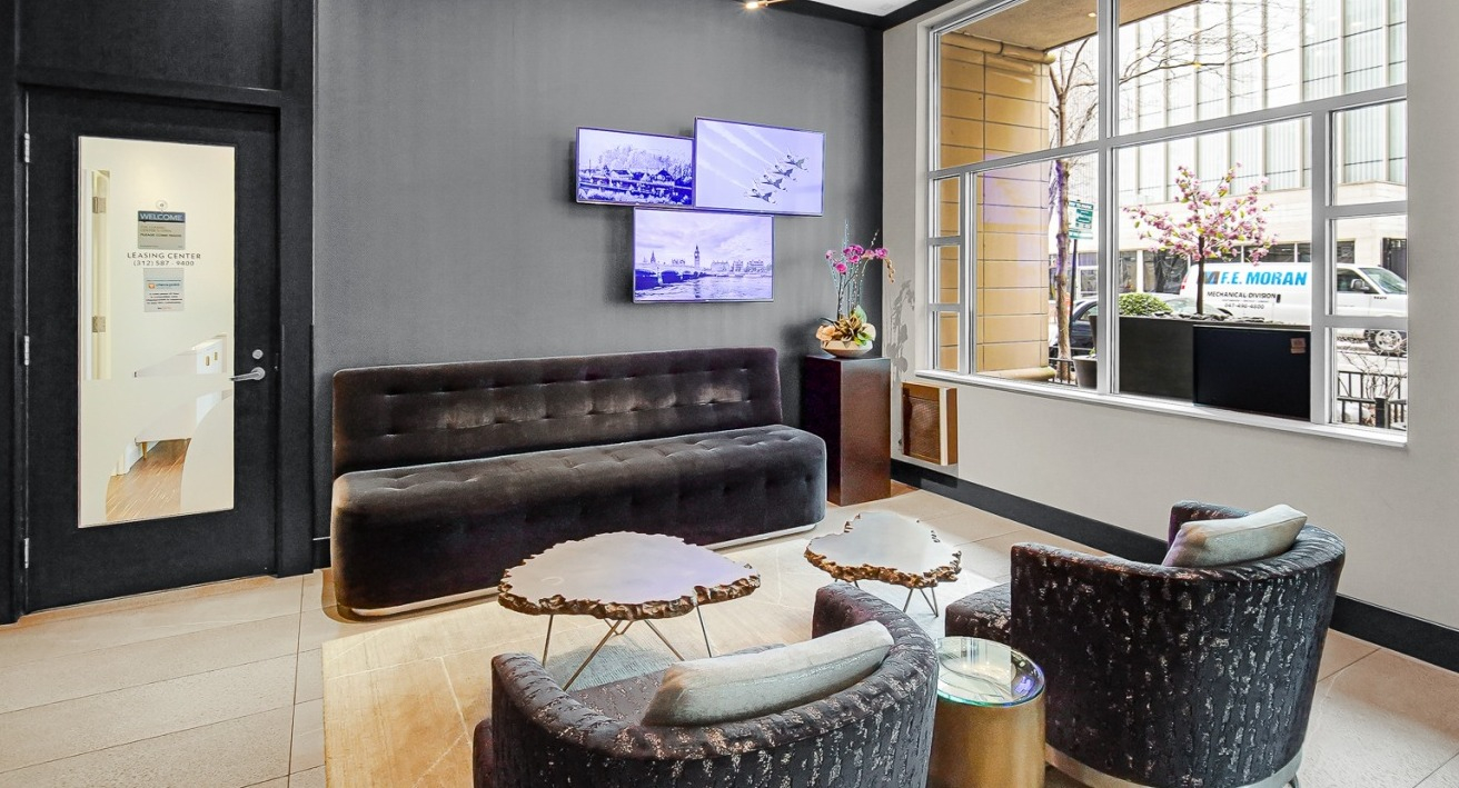 Stylish lobby at One Superior Place Apartments with dark seating, modern lighting, and large windows welcoming natural light