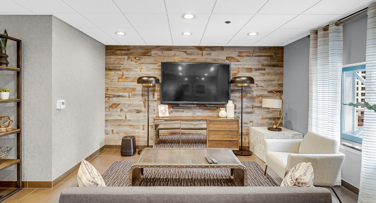 Cozy resident lounge at One Superior Place Apartments with rustic wood accent wall, mounted TV, and modern furnishings