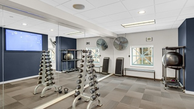 Yoga and strength training studio at One Superior Place Apartments with mirrored walls, free weights, and modern fitness equipment