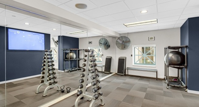 Yoga and strength training studio at One Superior Place Apartments with mirrored walls, free weights, and modern fitness equipment