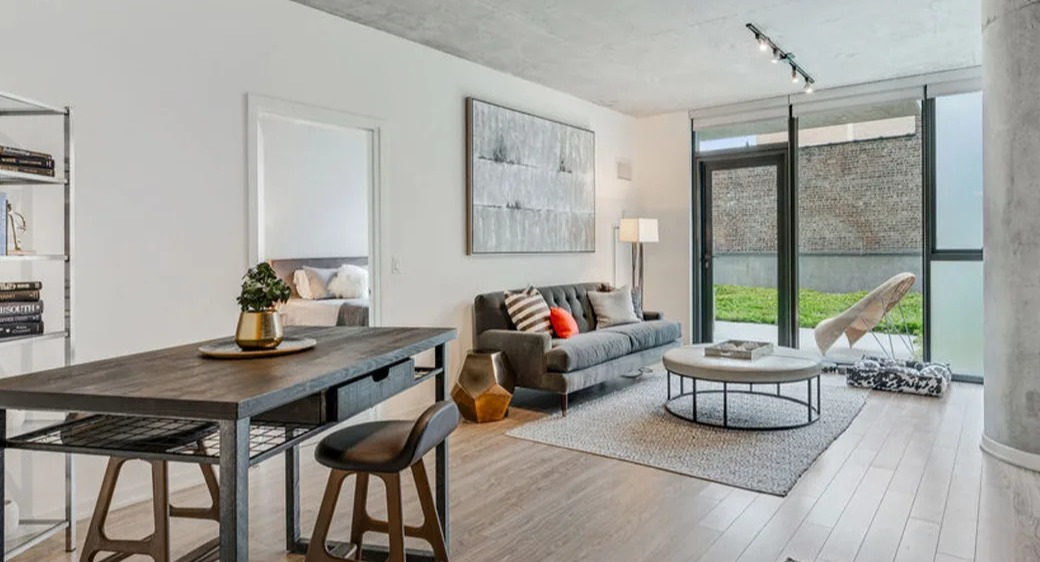 Bright living room at ONE333 apartments in Chicago with concrete ceiling, slider to patio and green space, plus flexible dining or home-office setu