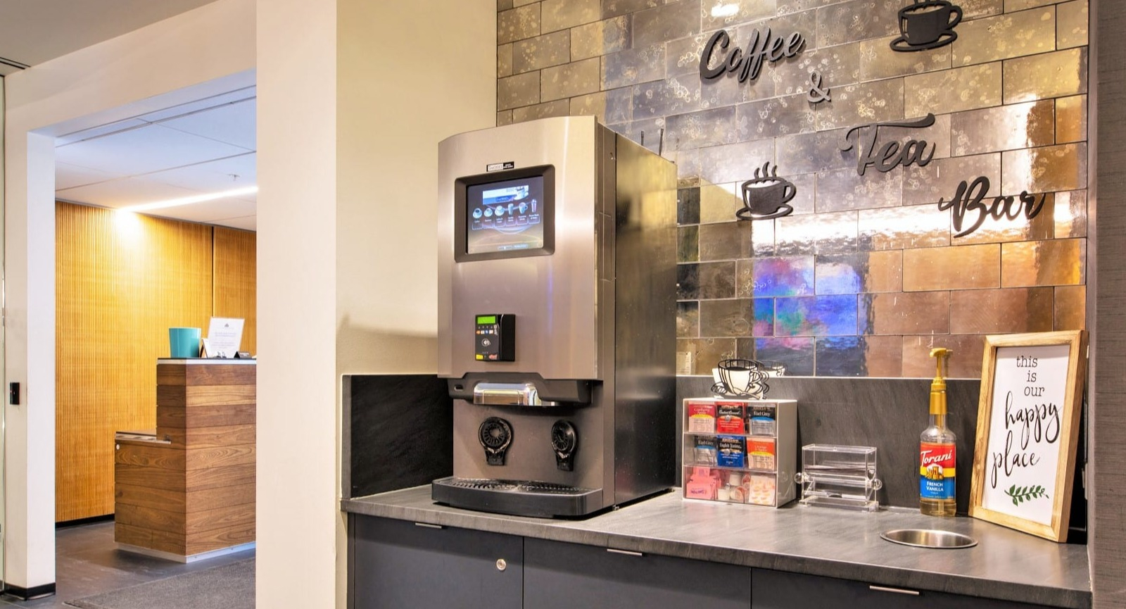 Resident coffee and tea bar at ONE333 apartments in Chicago with touchscreen brewer, condiments, and mirrored tile backsplash for quick morning pick-me-ups