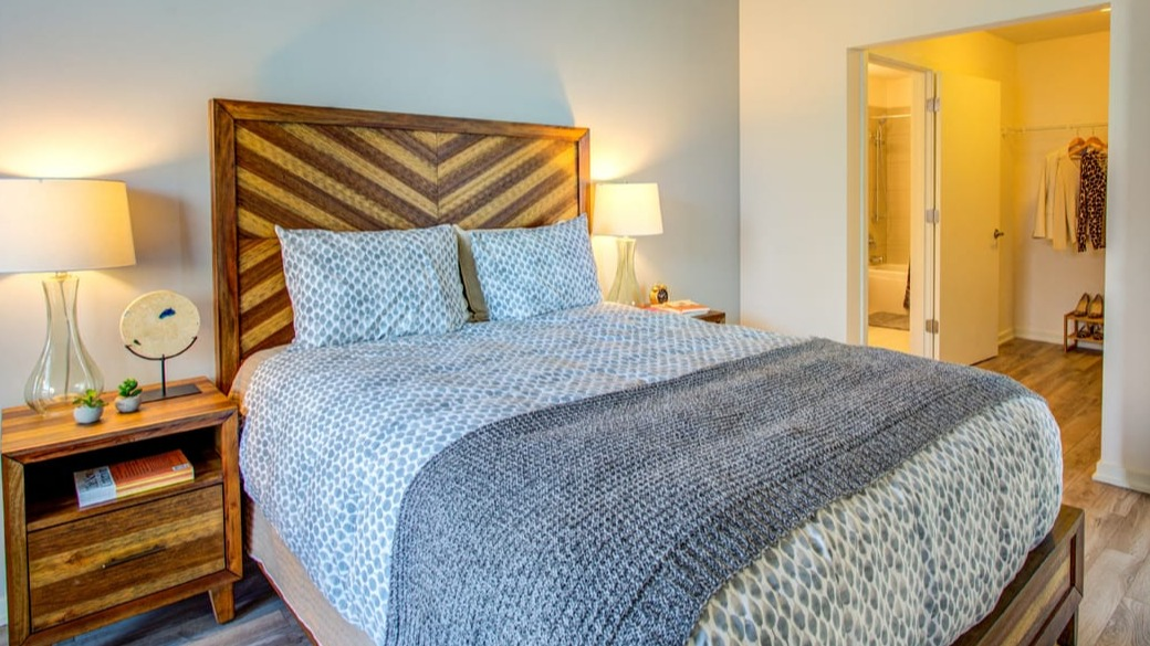 Warm bedroom with chevron wood headboard, soft lighting, and walk-in closet access at ONE333 apartments in Chicago for a cozy retreat near the bath