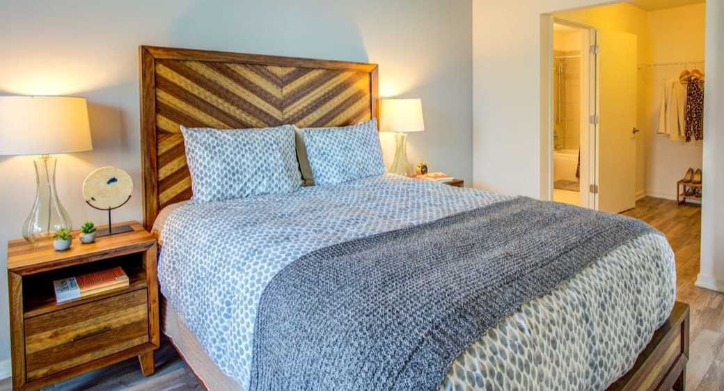 Warm bedroom with chevron wood headboard, soft lighting, and walk-in closet access at ONE333 apartments in Chicago for a cozy retreat near the bath