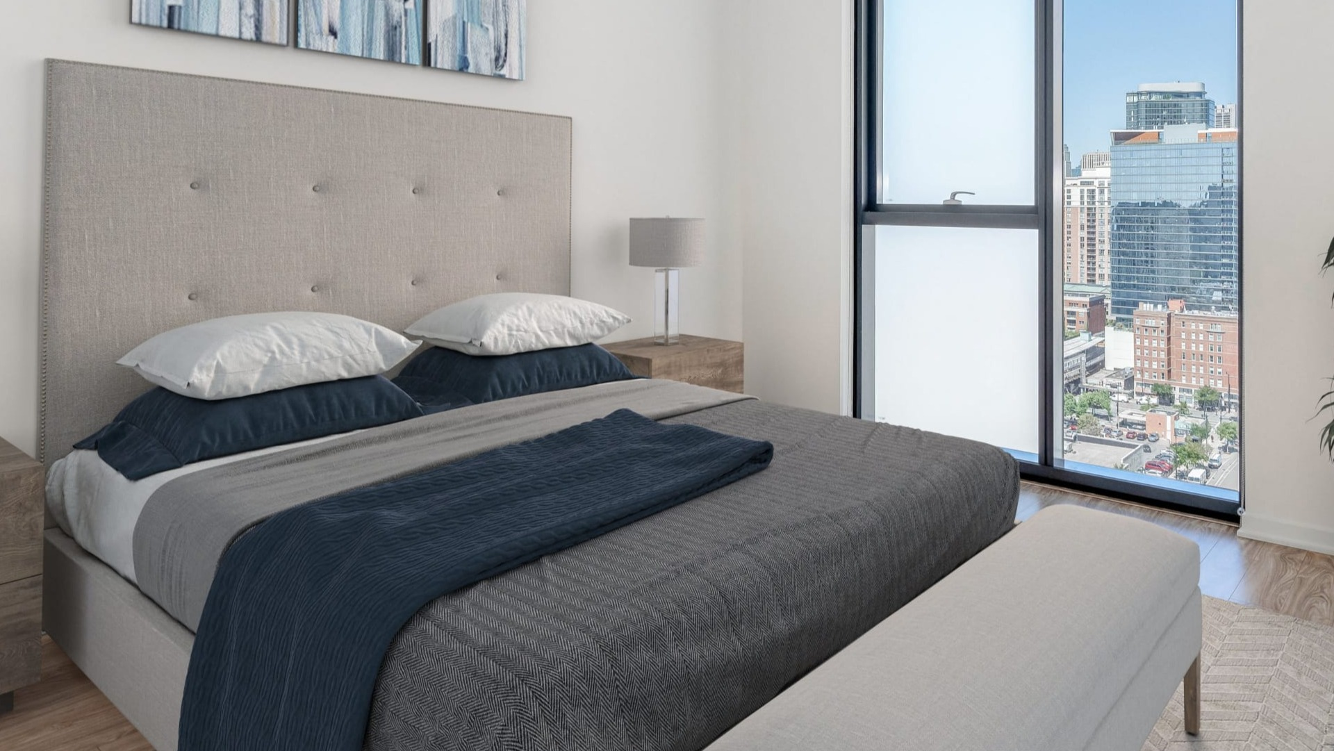 Cozy bedroom with upholstered headboard, bench, and abstract art, featuring a floor-to-ceiling window with city views at ONE333 in Chicago