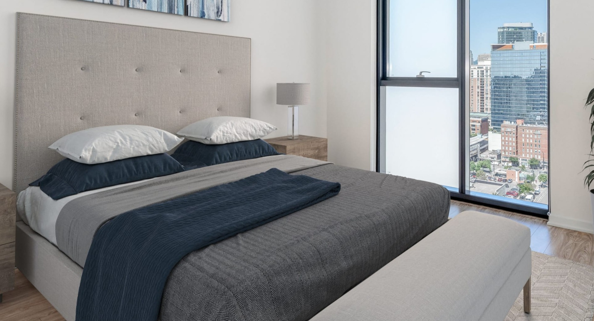 Cozy bedroom with upholstered headboard, bench, and abstract art, featuring a floor-to-ceiling window with city views at ONE333 in Chicago