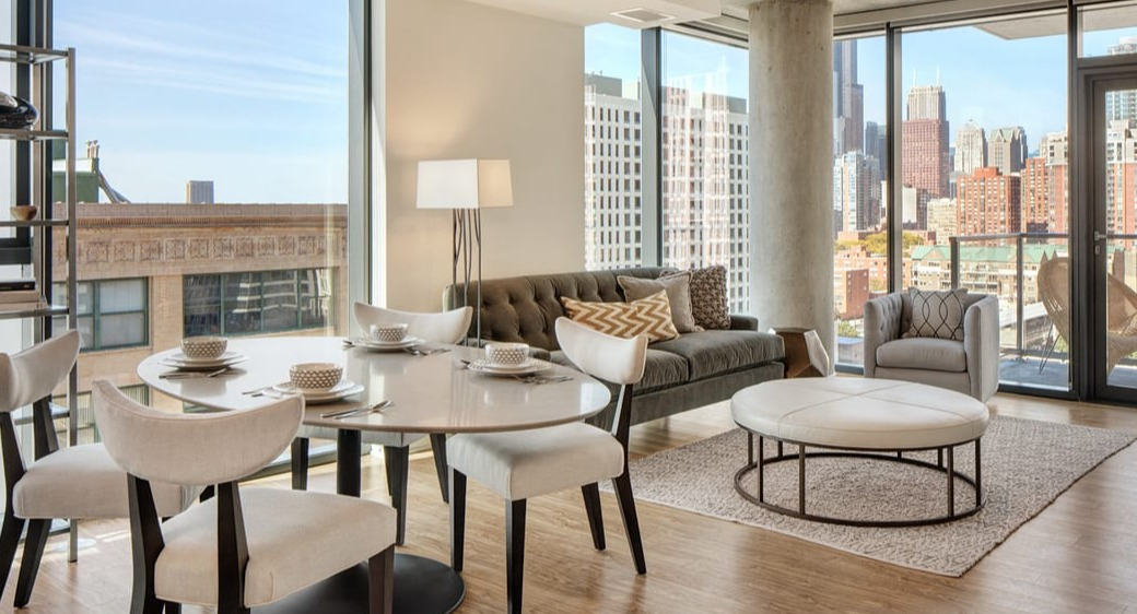 Cozy living and dining area with floor-to-ceiling windows, balcony access, and skyline views at ONE333 apartments in Chicago’s downtown