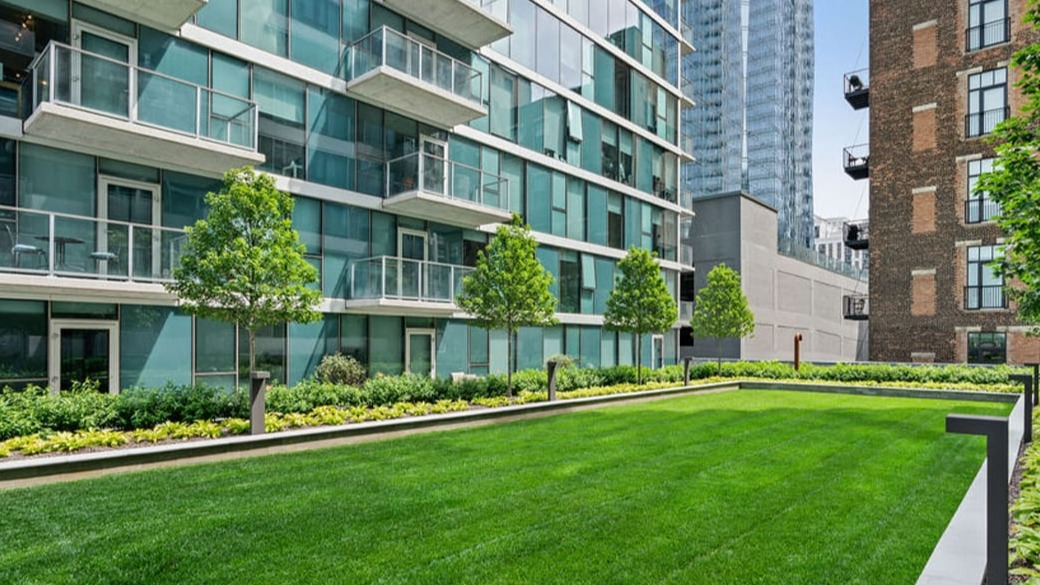 Landscaped green space courtyard at ONE333 apartments in Chicago with wide lawn, trees, and nearby balconies—great for pets, outdoor play, and relaxing