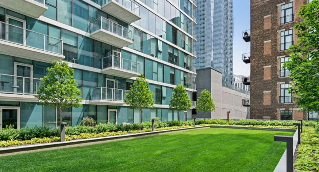Landscaped green space courtyard at ONE333 apartments in Chicago with wide lawn, trees, and nearby balconies—great for pets, outdoor play, and relaxing