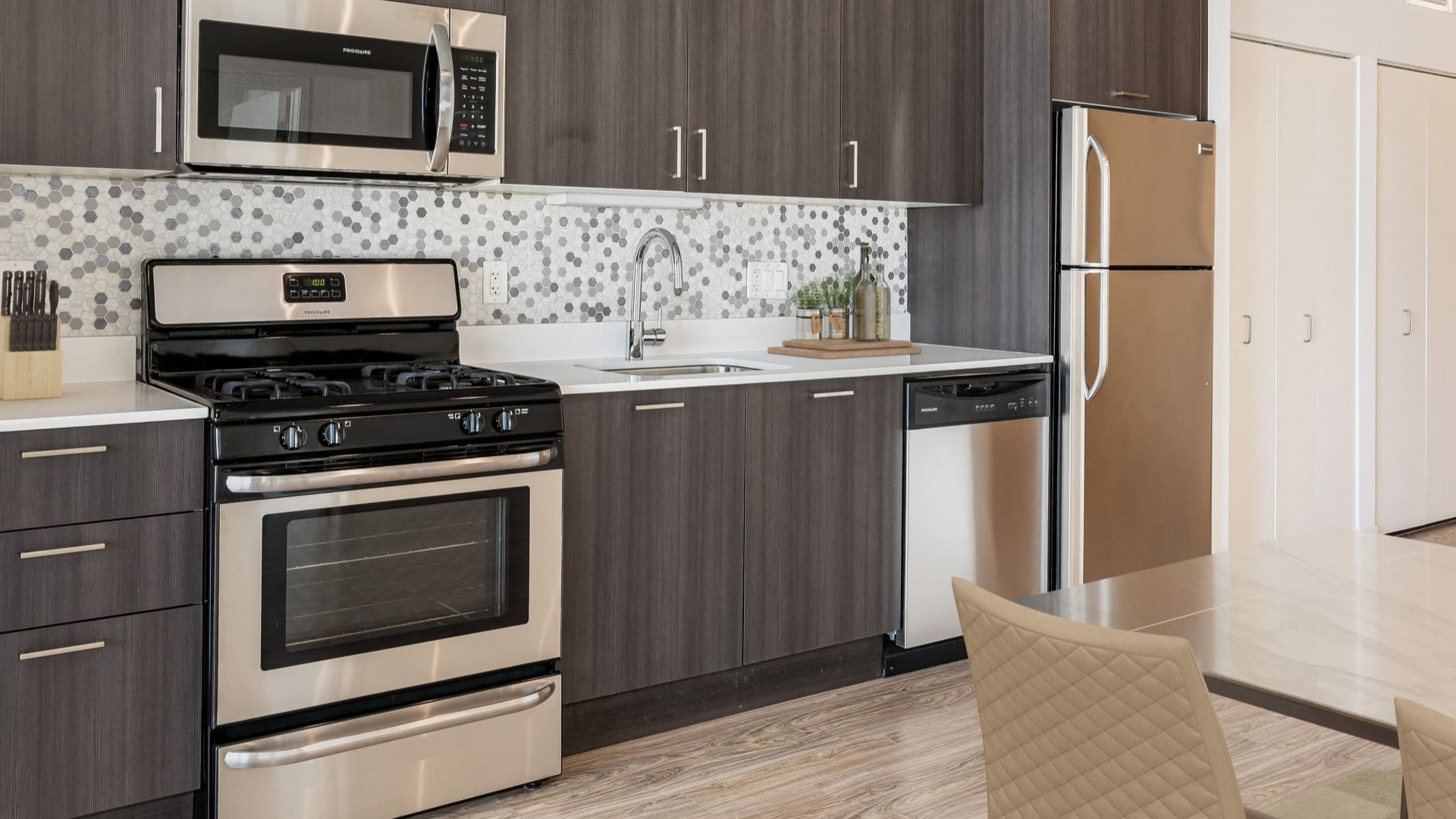 Contemporary kitchen with gray cabinets, stainless appliances, and hex mosaic backsplash at ONE333 apartments in Chicago—stylish and functional for everyday cooking