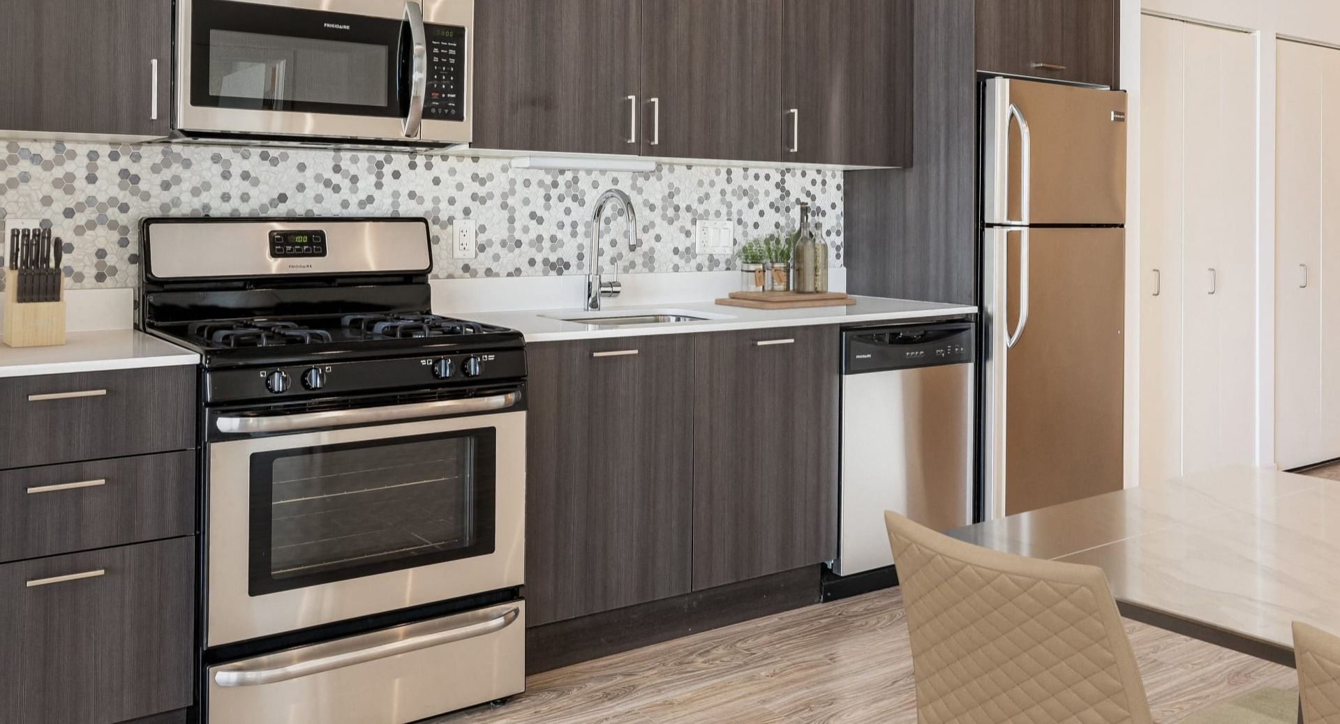 Contemporary kitchen with gray cabinets, stainless appliances, and hex mosaic backsplash at ONE333 apartments in Chicago—stylish and functional for everyday cooking