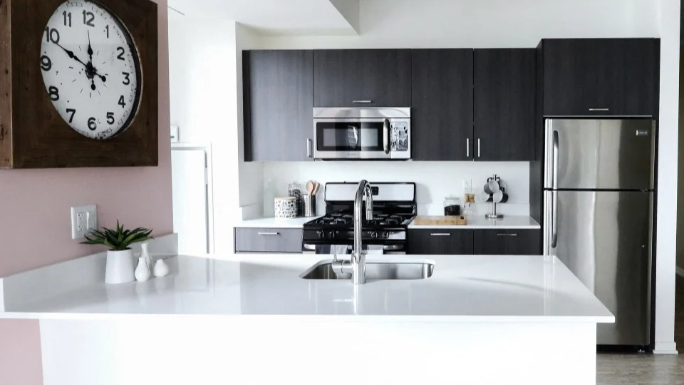 Modern kitchen at ONE333 apartments in Chicago featuring a bright peninsula with sink and bar seating, gray cabinets, and stainless steel appliances