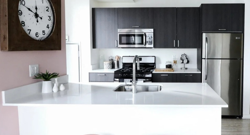 Modern kitchen at ONE333 apartments in Chicago featuring a bright peninsula with sink and bar seating, gray cabinets, and stainless steel appliances