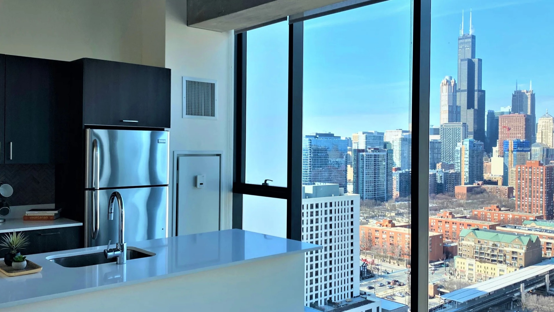 Sleek kitchen with quartz island, stainless appliances, and floor-to-ceiling windows showcasing Chicago skyline at ONE333