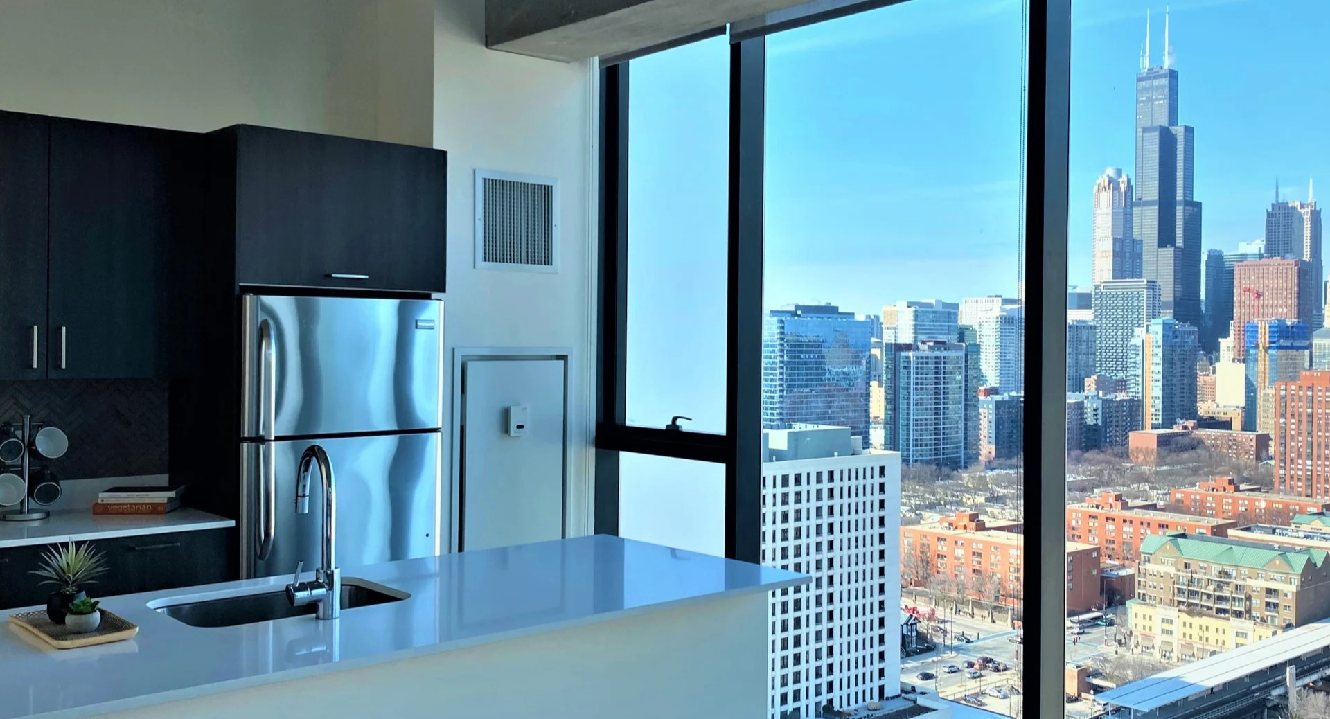 Sleek kitchen with quartz island, stainless appliances, and floor-to-ceiling windows showcasing Chicago skyline at ONE333