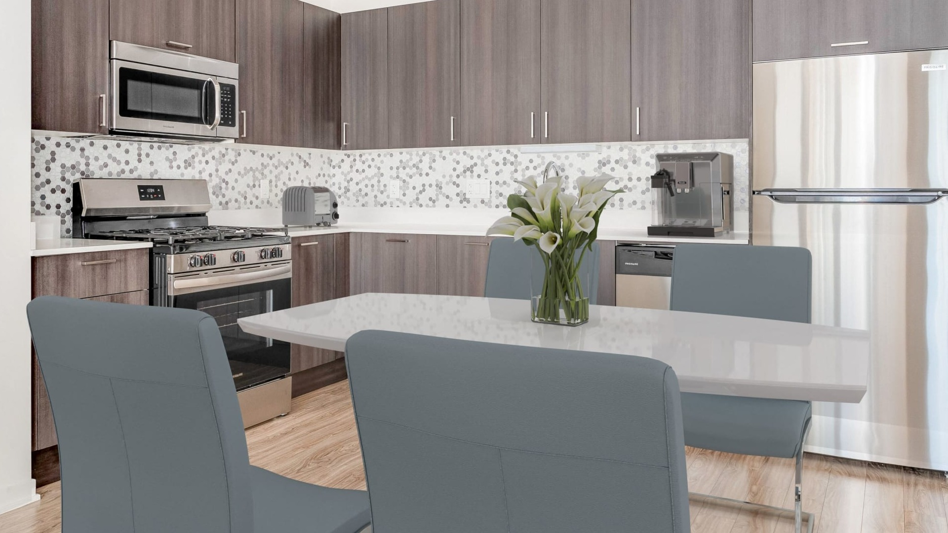 Contemporary kitchen with gray cabinets, hex tile backsplash, stainless appliances, and dining area at ONE333 apartments in Chicago