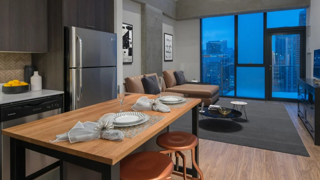 Open-concept kitchen and living room with wood island, stainless appliances, and dramatic tall windows overlooking Chicago at ONE333 apartments—great for entertaining