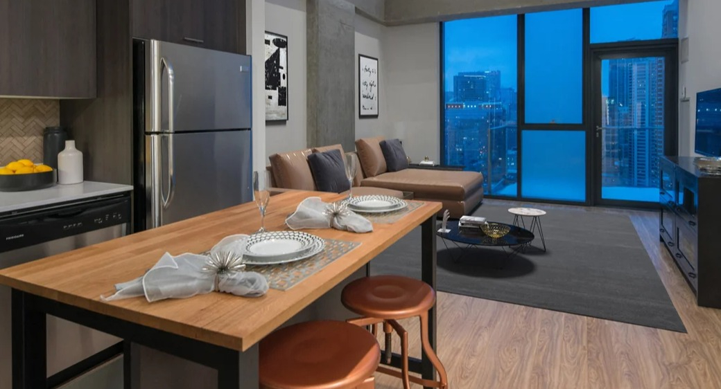 Open-concept kitchen and living room with wood island, stainless appliances, and dramatic tall windows overlooking Chicago at ONE333 apartments—great for entertaining