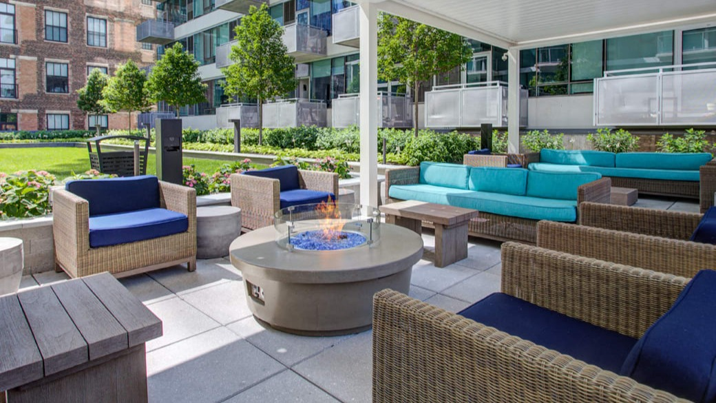 Outdoor lounge with fire pit, wicker seating, and landscaped courtyard at ONE333 apartments in Chicago, ideal for relaxing and hosting friends