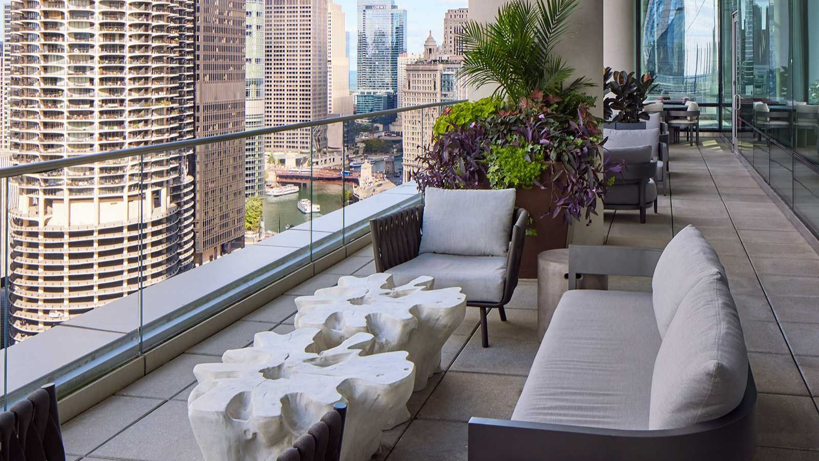 Spacious balcony at OneEleven in Chicago, featuring comfortable seating, lush plants, and panoramic city and river views