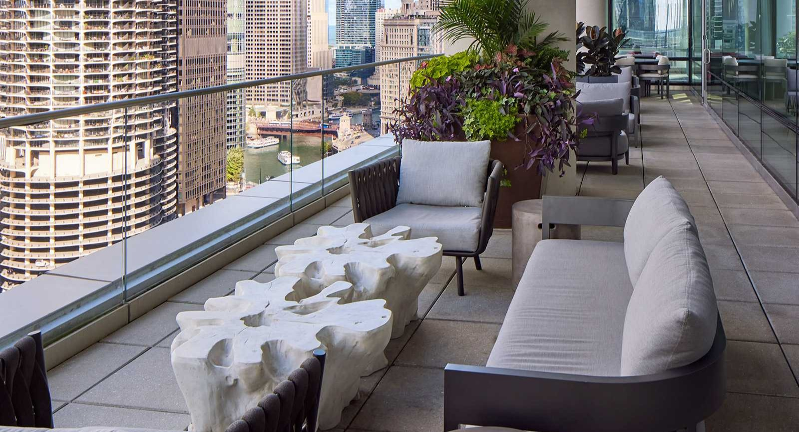Spacious balcony at OneEleven in Chicago, featuring comfortable seating, lush plants, and panoramic city and river views