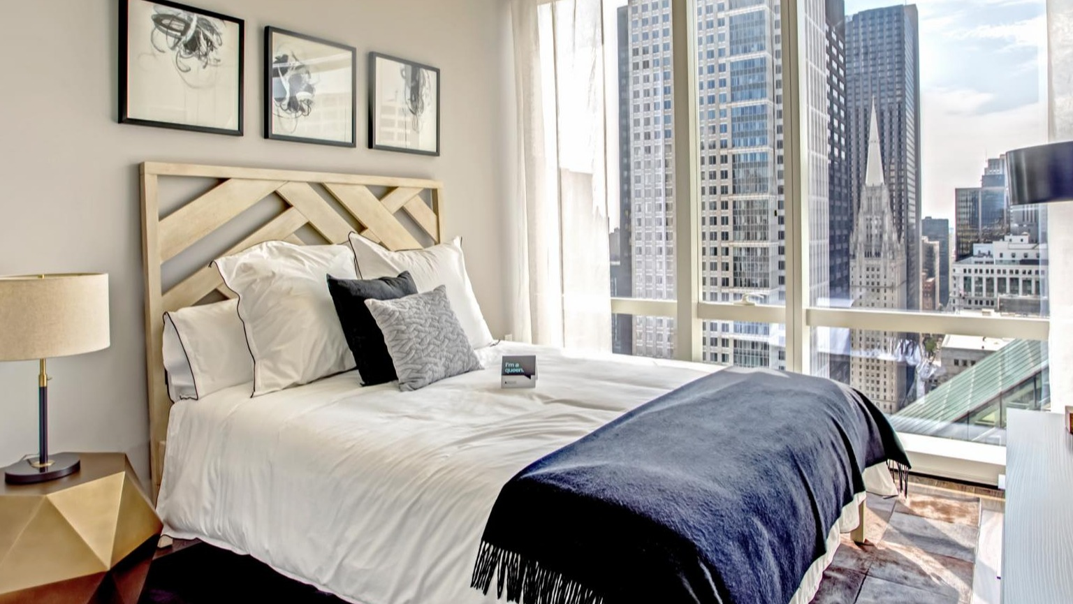 Contemporary bedroom at OneEleven in Chicago, featuring a stylish bed, modern decor, and stunning city skyline views through large windows