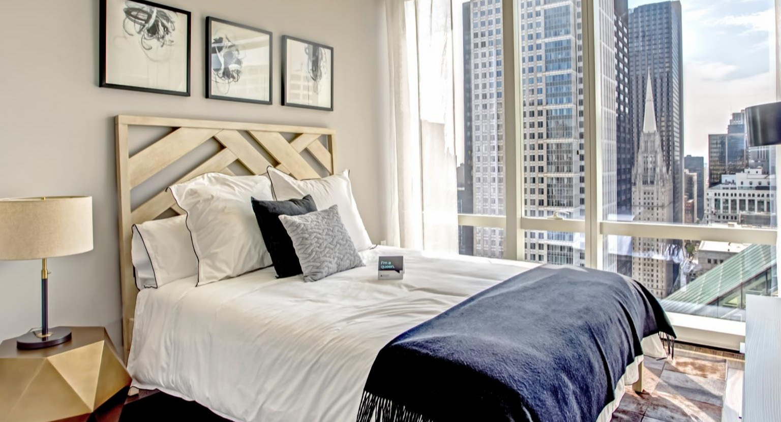 Contemporary bedroom at OneEleven in Chicago, featuring a stylish bed, modern decor, and stunning city skyline views through large windows