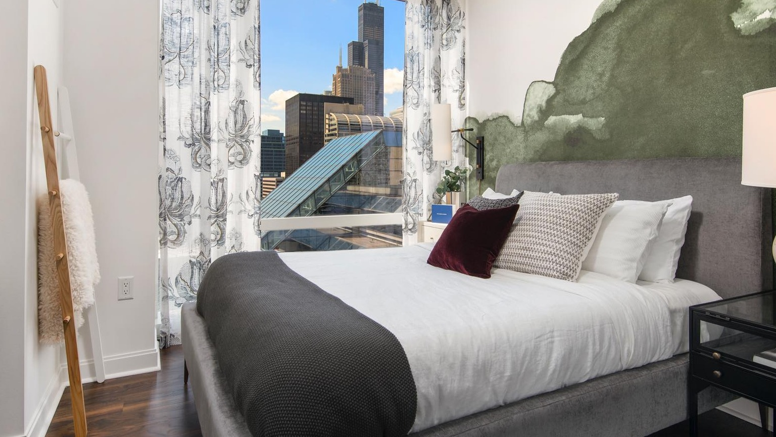 Modern bedroom at OneEleven in Chicago, featuring a comfortable bed, stylish decor, and floor-to-ceiling windows with city views