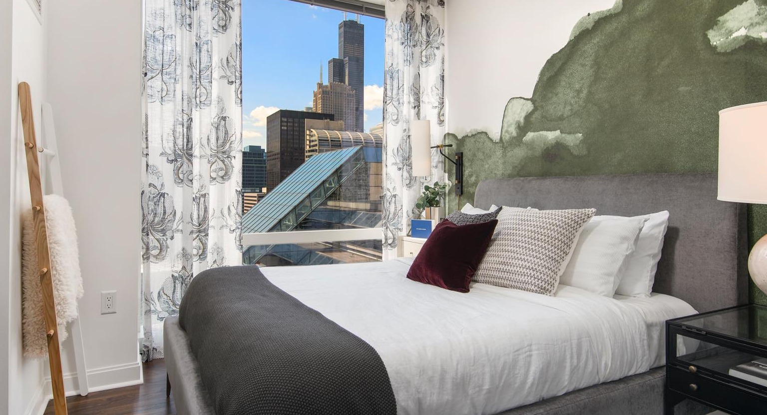 Modern bedroom at OneEleven in Chicago, featuring a comfortable bed, stylish decor, and floor-to-ceiling windows with city views
