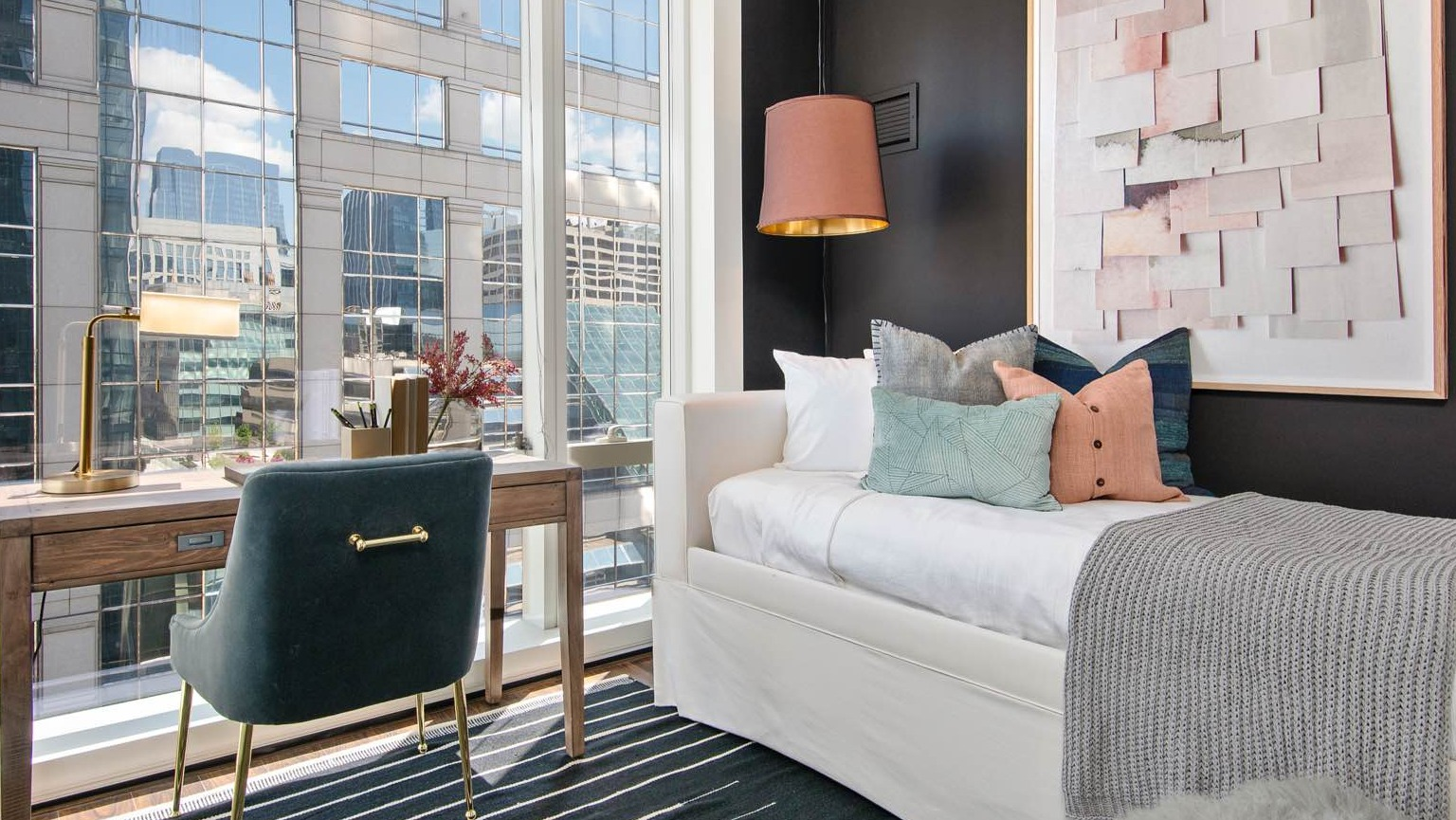 Stylish bedroom at OneEleven in Chicago, featuring a cozy daybed, a functional desk area, and large windows with urban views