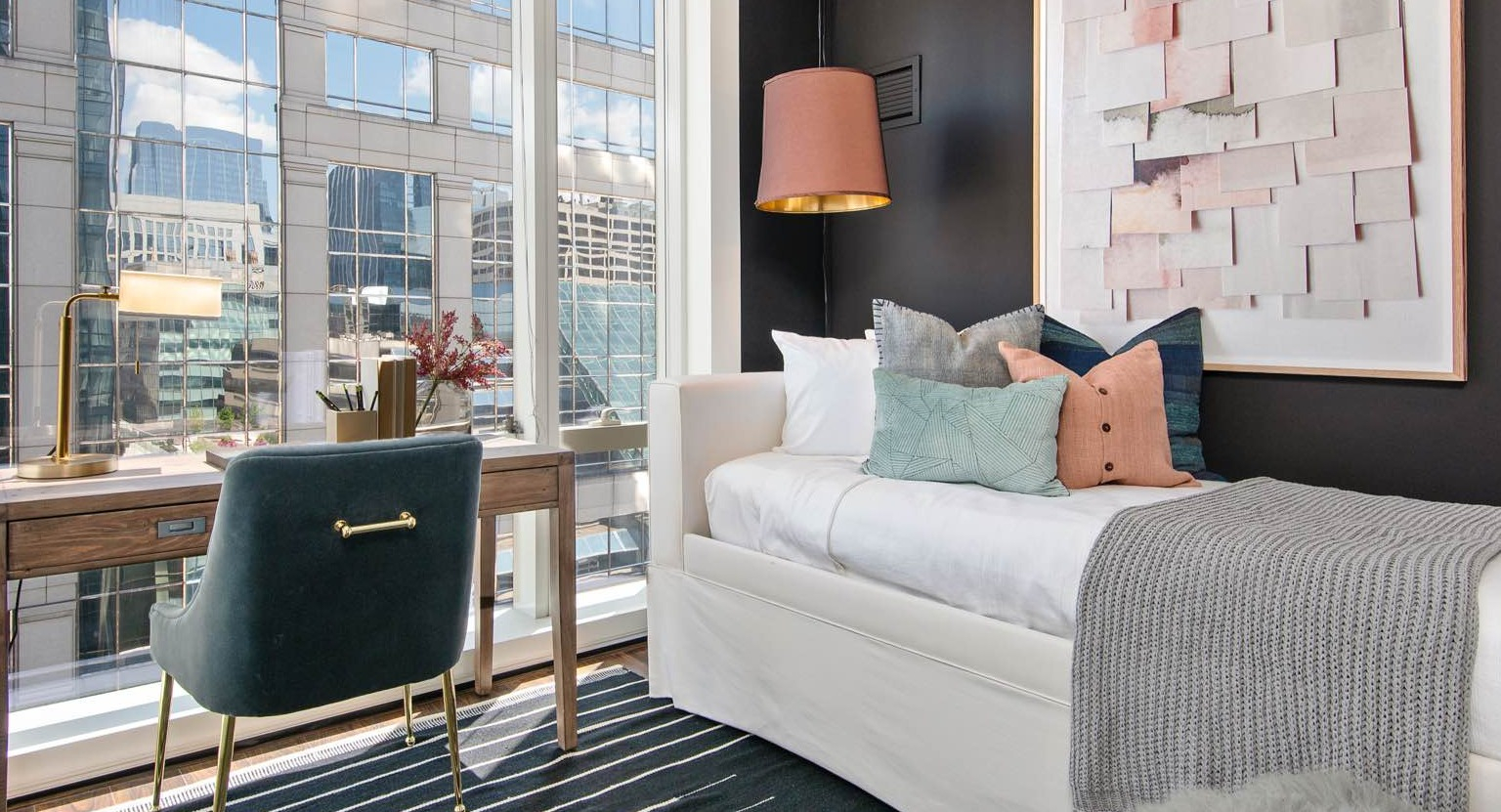 Stylish bedroom at OneEleven in Chicago, featuring a cozy daybed, a functional desk area, and large windows with urban views