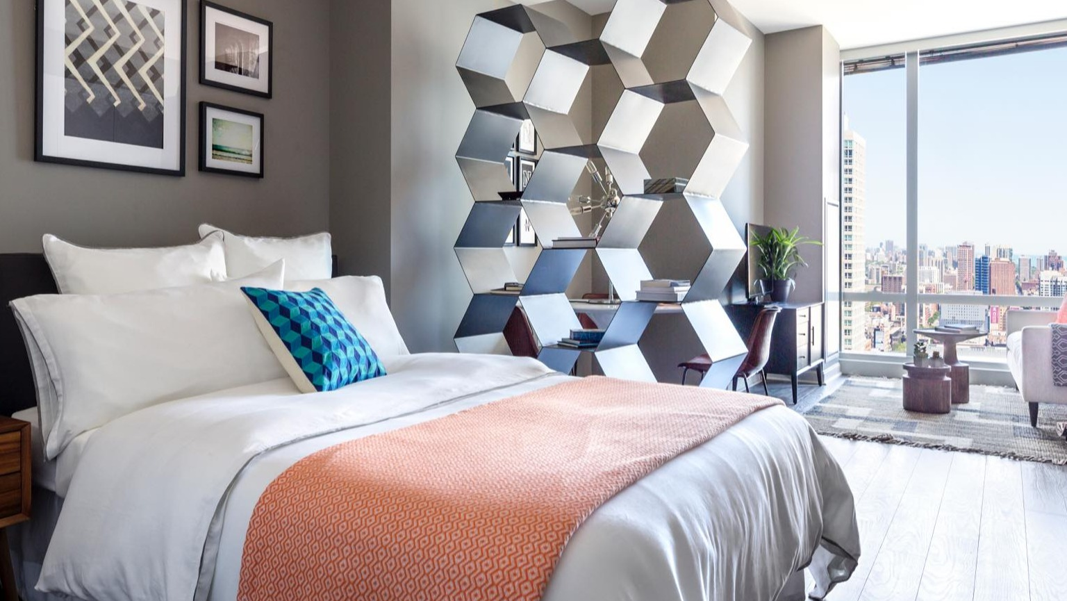 Unique loft-style bedroom at OneEleven in Chicago, featuring a modern bed, decorative shelving, and large windows with urban views