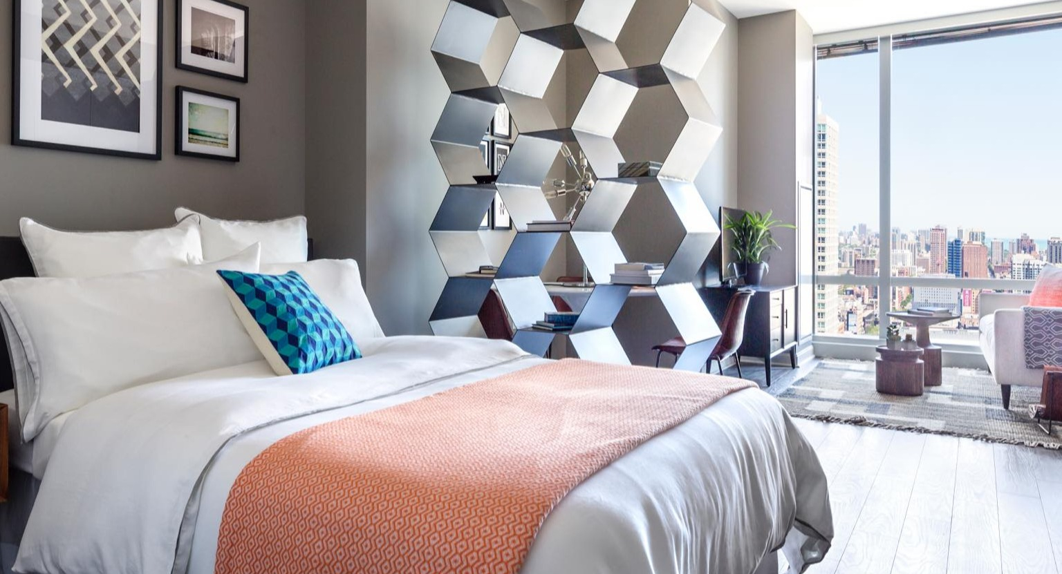 Unique loft-style bedroom at OneEleven in Chicago, featuring a modern bed, decorative shelving, and large windows with urban views