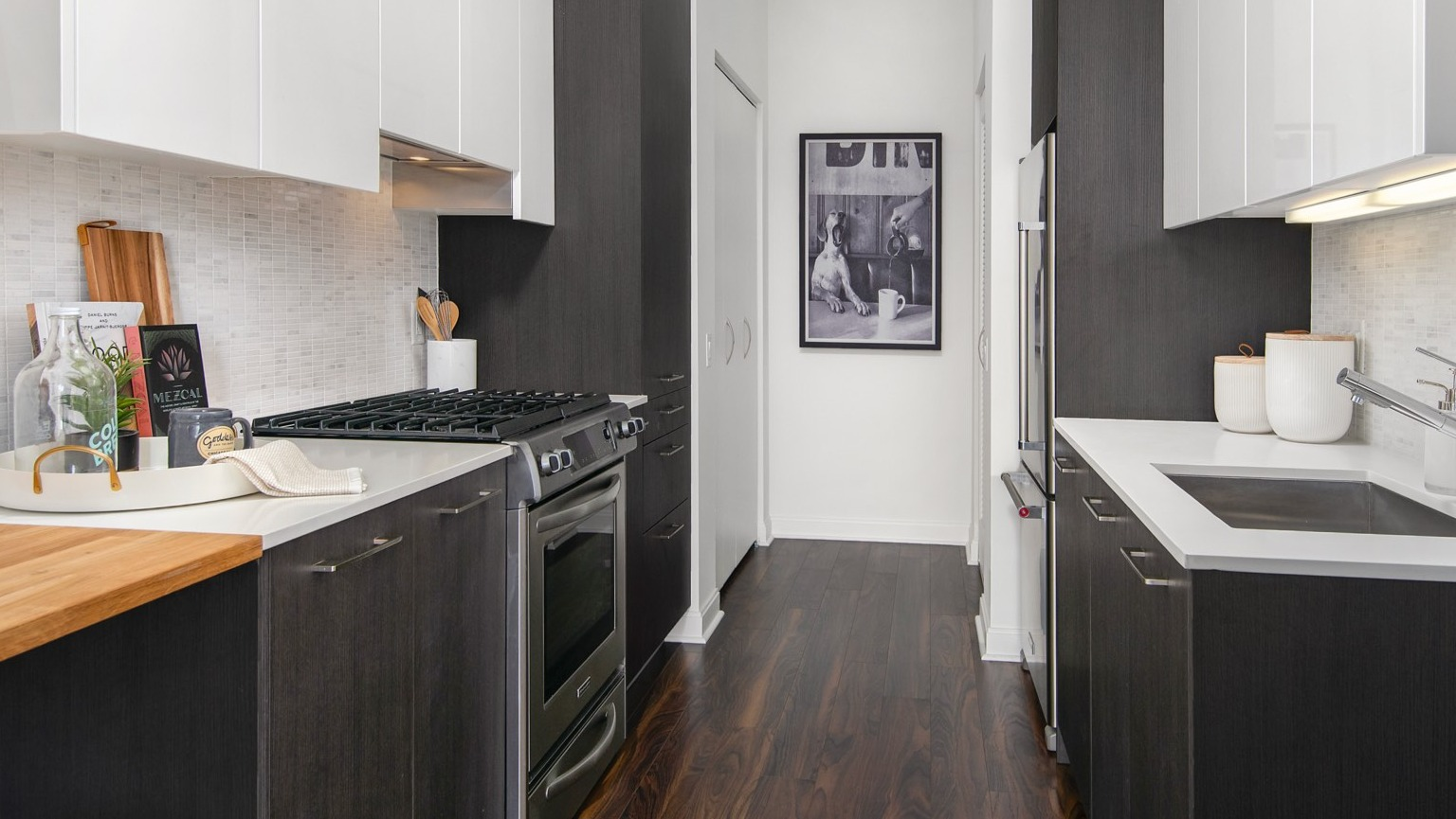 Sleek galley kitchen at OneEleven in Chicago, featuring dark lower cabinets, white upper cabinets, and modern stainless steel appliances