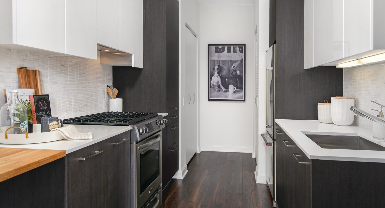 Sleek galley kitchen at OneEleven in Chicago, featuring dark lower cabinets, white upper cabinets, and modern stainless steel appliances