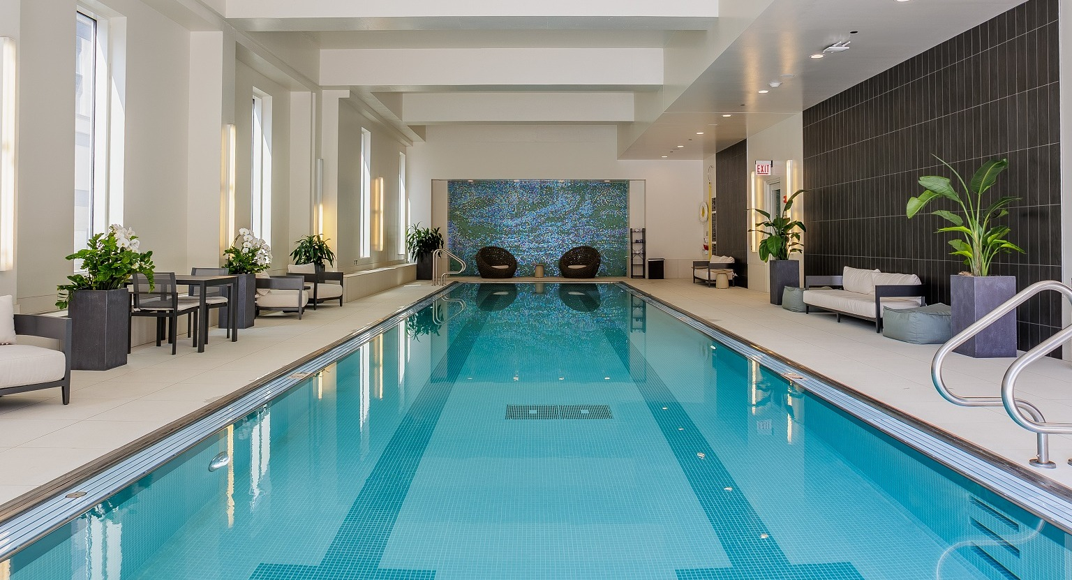 Serene indoor lap pool at OneEleven in Chicago, featuring clear blue water, comfortable seating areas, and ambient lighting
