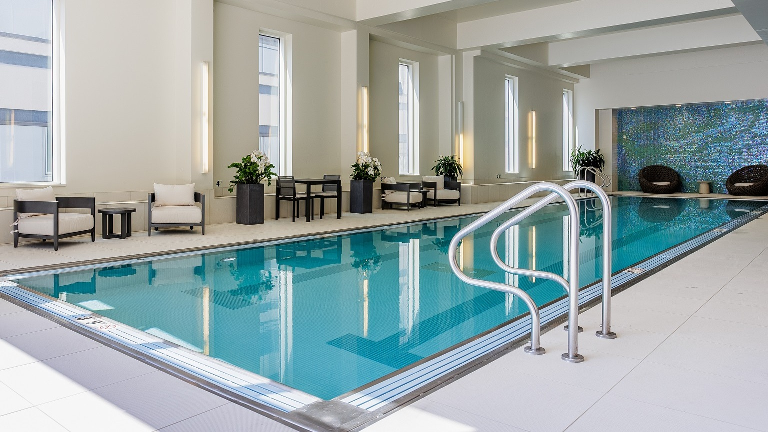 Inviting indoor pool area at OneEleven in Chicago, featuring a pristine lap pool, comfortable lounge seating, and large windows