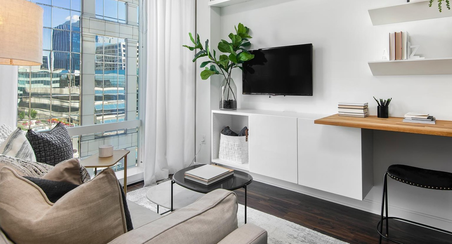 Modern living room at OneEleven in Chicago, featuring a comfortable sofa, built-in desk, shelving, and large windows with city views