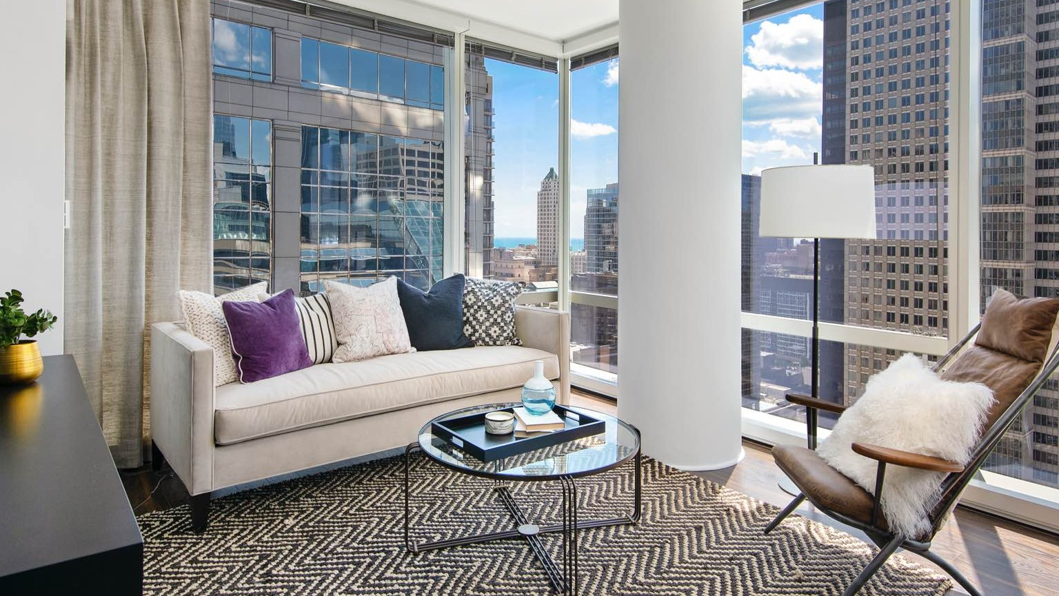 Chic apartment living room at OneEleven in Chicago, featuring a comfortable sofa, modern rug, and expansive city skyline views