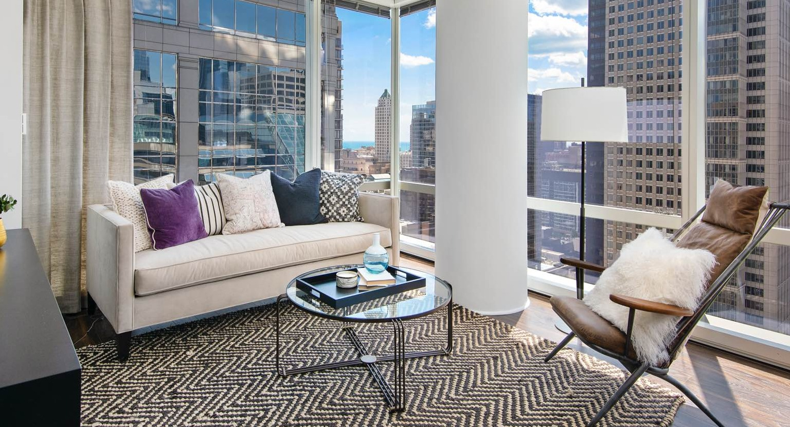 Chic apartment living room at OneEleven in Chicago, featuring a comfortable sofa, modern rug, and expansive city skyline views