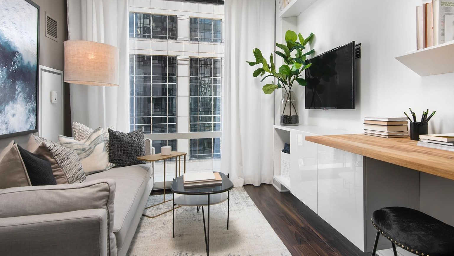 Cozy living room at OneEleven in Chicago, featuring a comfortable sofa, wall-mounted shelves, and an integrated workspace with urban views