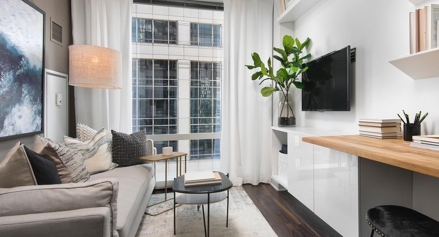 Cozy living room at OneEleven in Chicago, featuring a comfortable sofa, wall-mounted shelves, and an integrated workspace with urban views