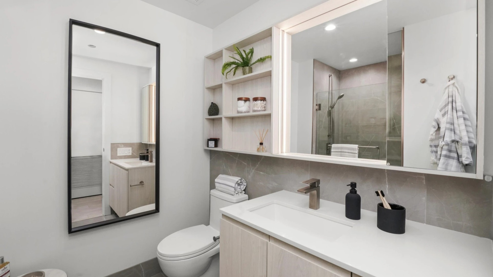 Modern apartment bathroom at Onni Fulton Market in Chicago, featuring a sleek vanity, mirror, and a contemporary toilet