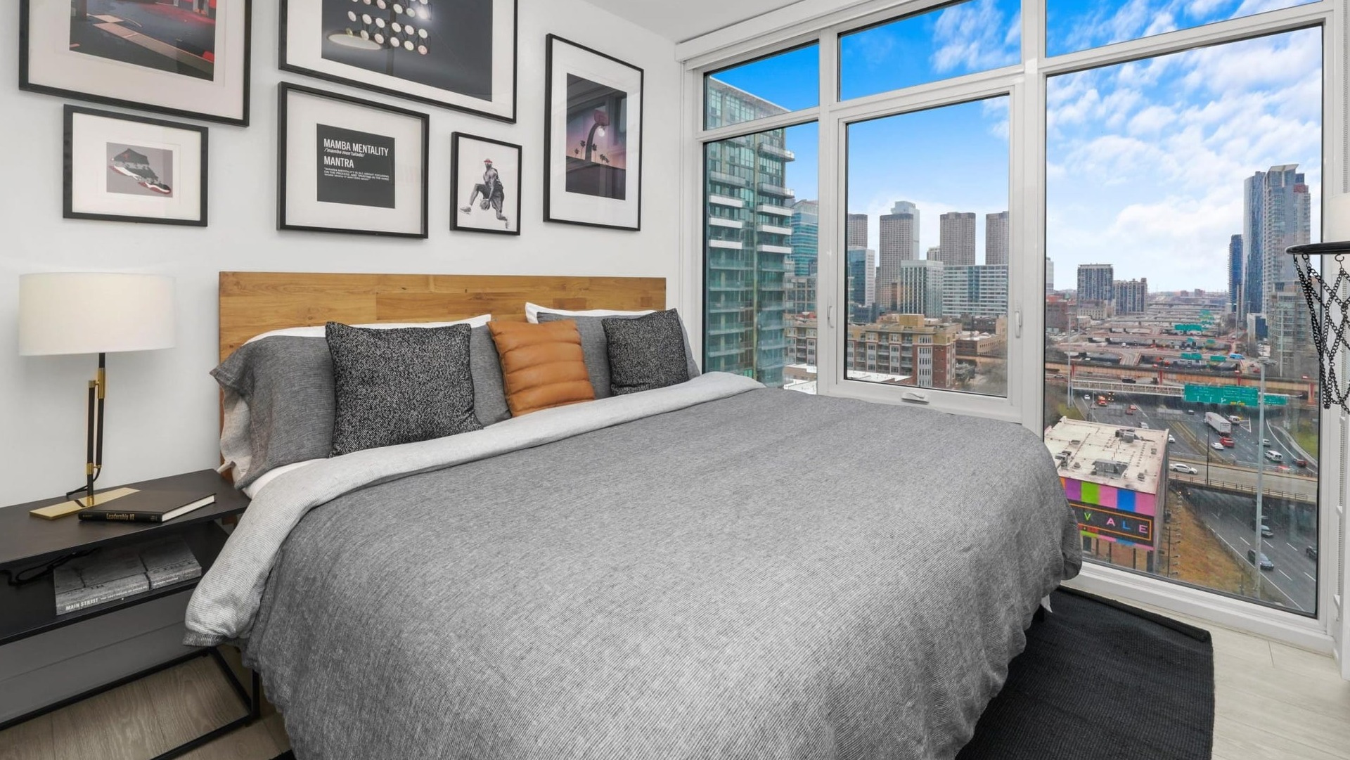 Vibrant bedroom at Onni Fulton Market in Chicago, featuring a comfortable bed, a striking gallery wall, and large windows with urban views