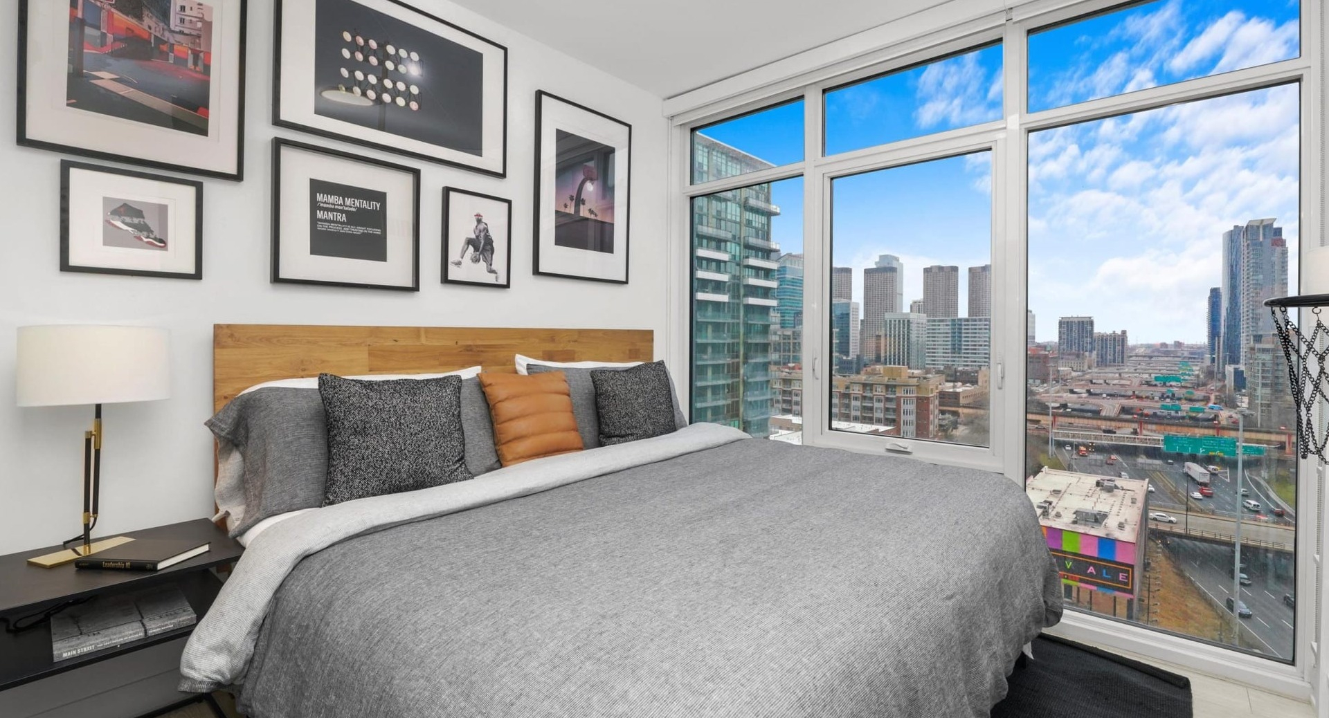 Vibrant bedroom at Onni Fulton Market in Chicago, featuring a comfortable bed, a striking gallery wall, and large windows with urban views