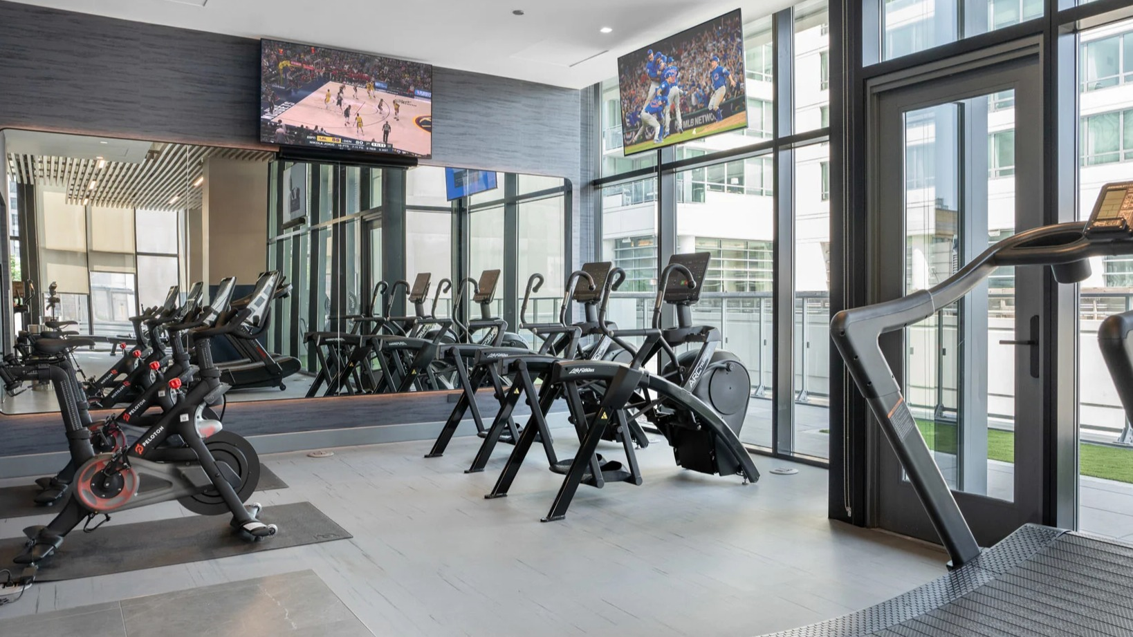 Modern cardio gym at Onni Fulton Market in Chicago, featuring treadmills, ellipticals, spin bikes, and TVs for an engaging workout
