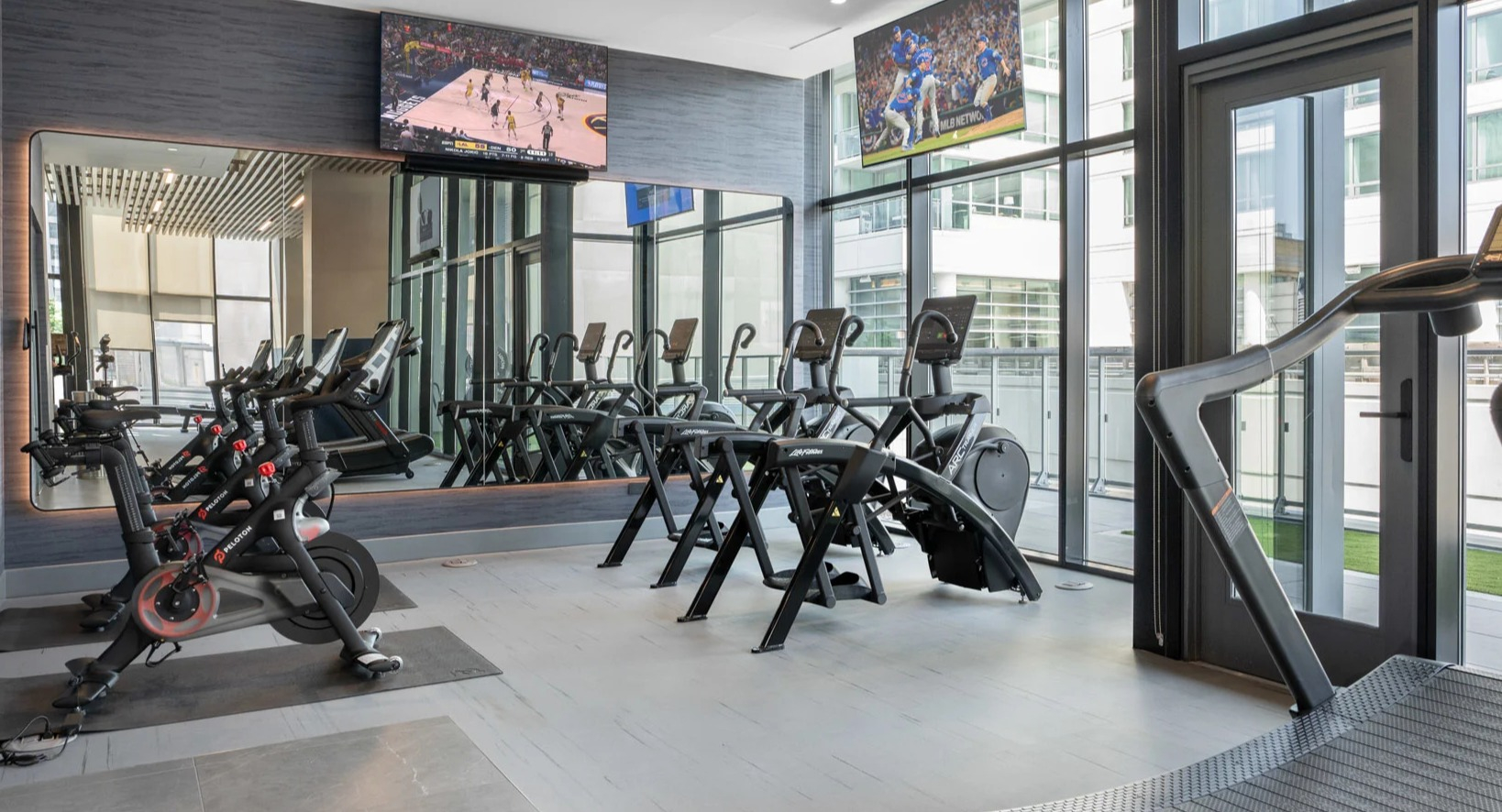 Modern cardio gym at Onni Fulton Market in Chicago, featuring treadmills, ellipticals, spin bikes, and TVs for an engaging workout